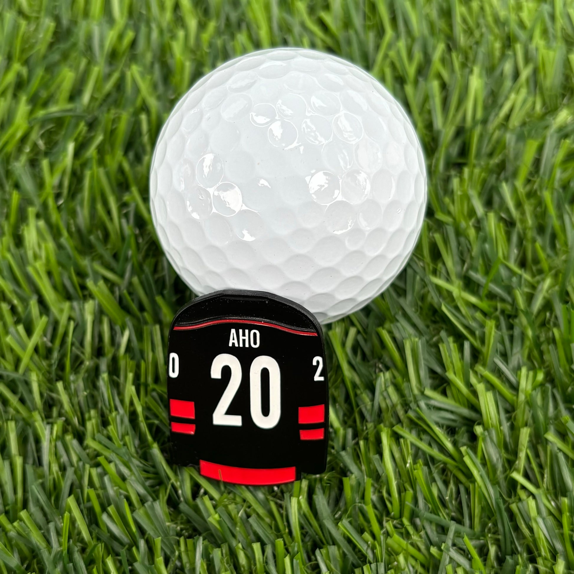 Sebastian Aho golf ball marker and golf ball on grass - stylish and durable golf accessory for fans and golfers