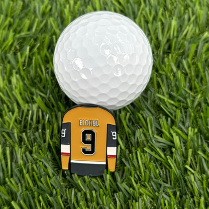 Jack Eichel golf ball marker shaped like a jersey on grass next to a golf ball