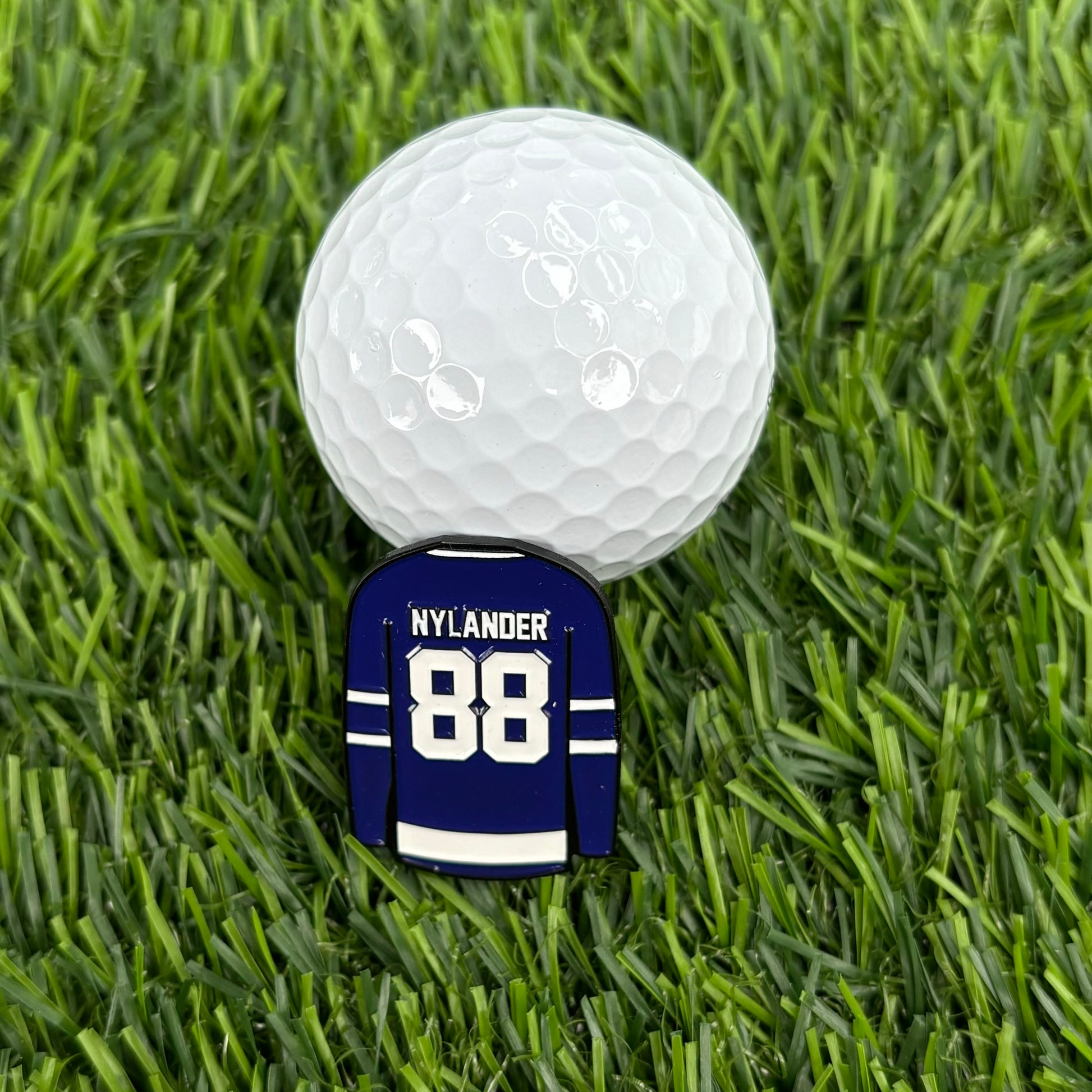 William Nylander golf ball marker on grass beside a golf ball, stylish and durable premium golf accessory for fans and enthusiasts