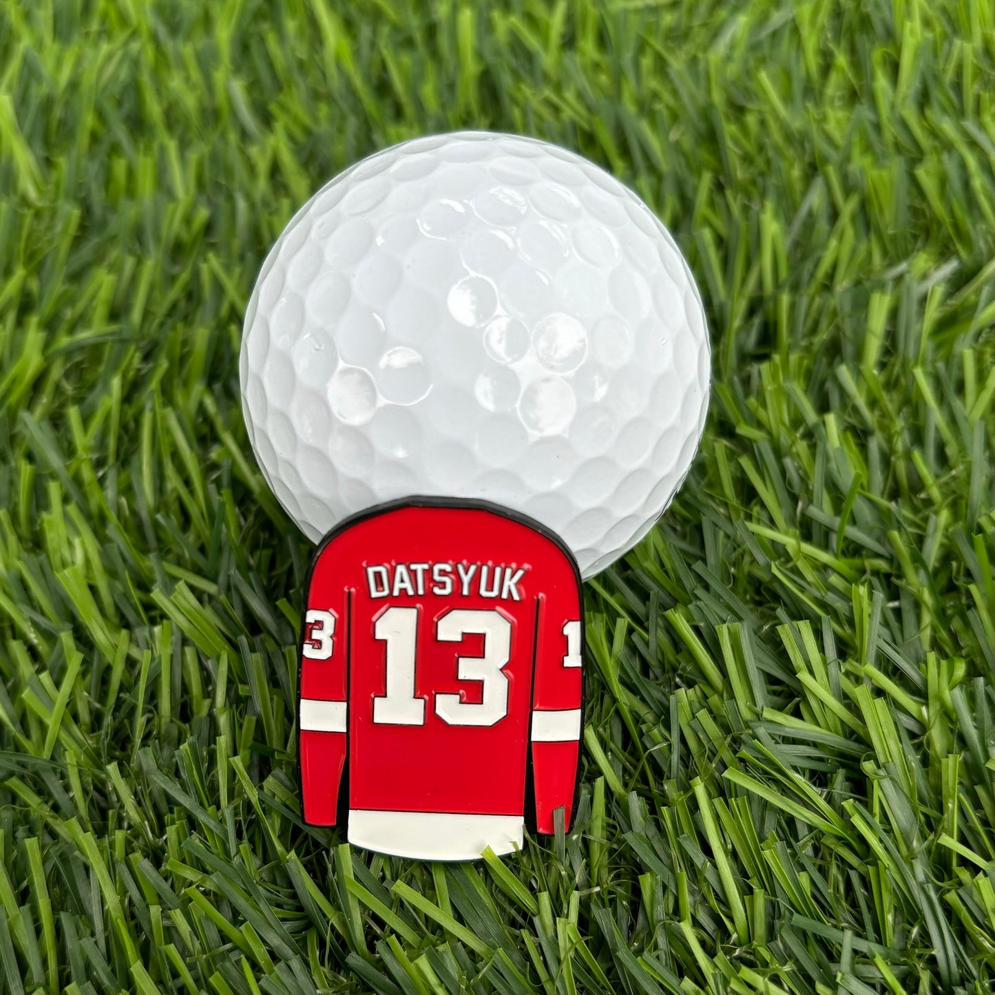 Pavel Datsyuk golf ball marker on grass with hockey jersey design - a stylish, unique, high-quality, and durable golf accessory for golfers