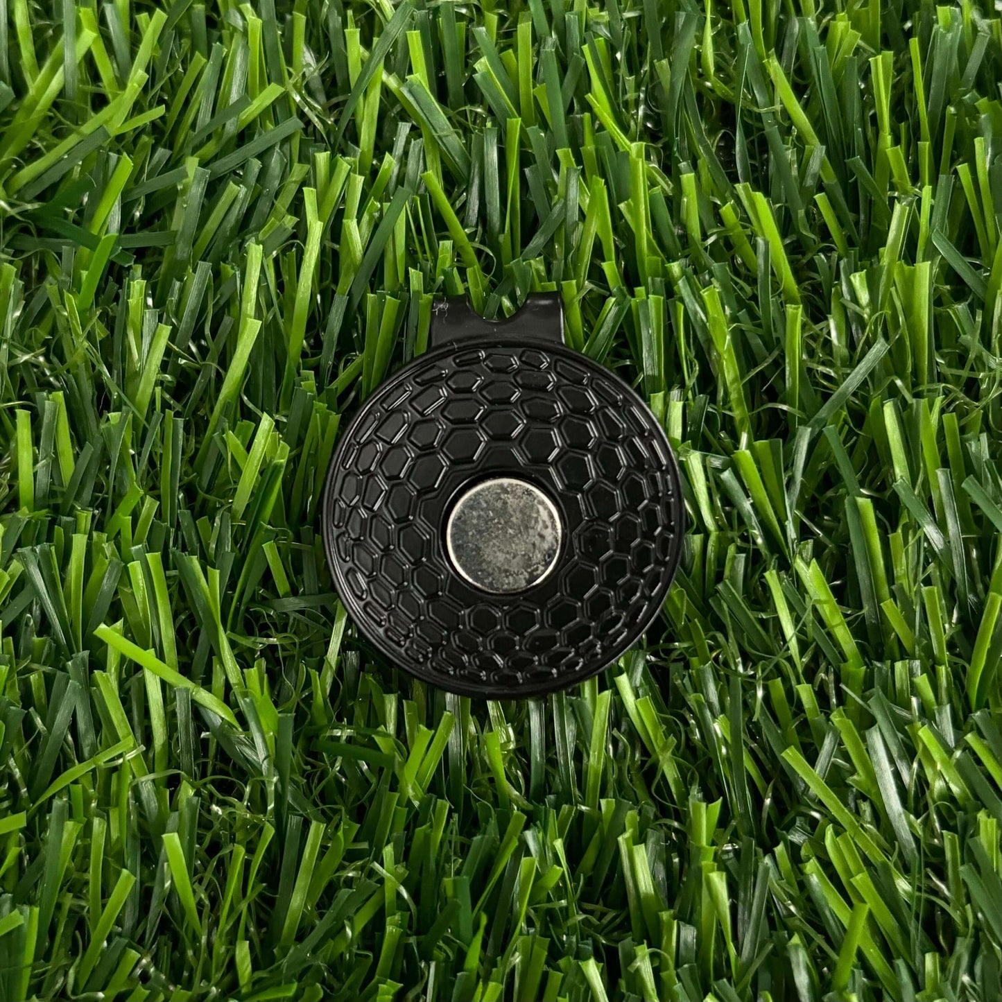 Premium durable black golf ball marker on grass, perfect golfing accessory for golf enthusiasts and players.