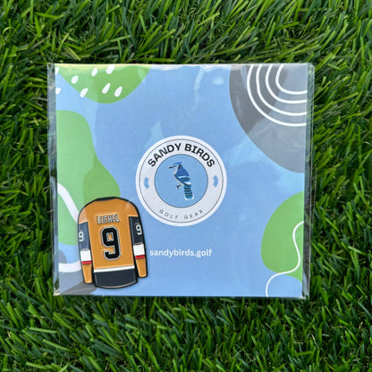 Jack Eichel golf ball marker and Sandy Birds packaging on green grass