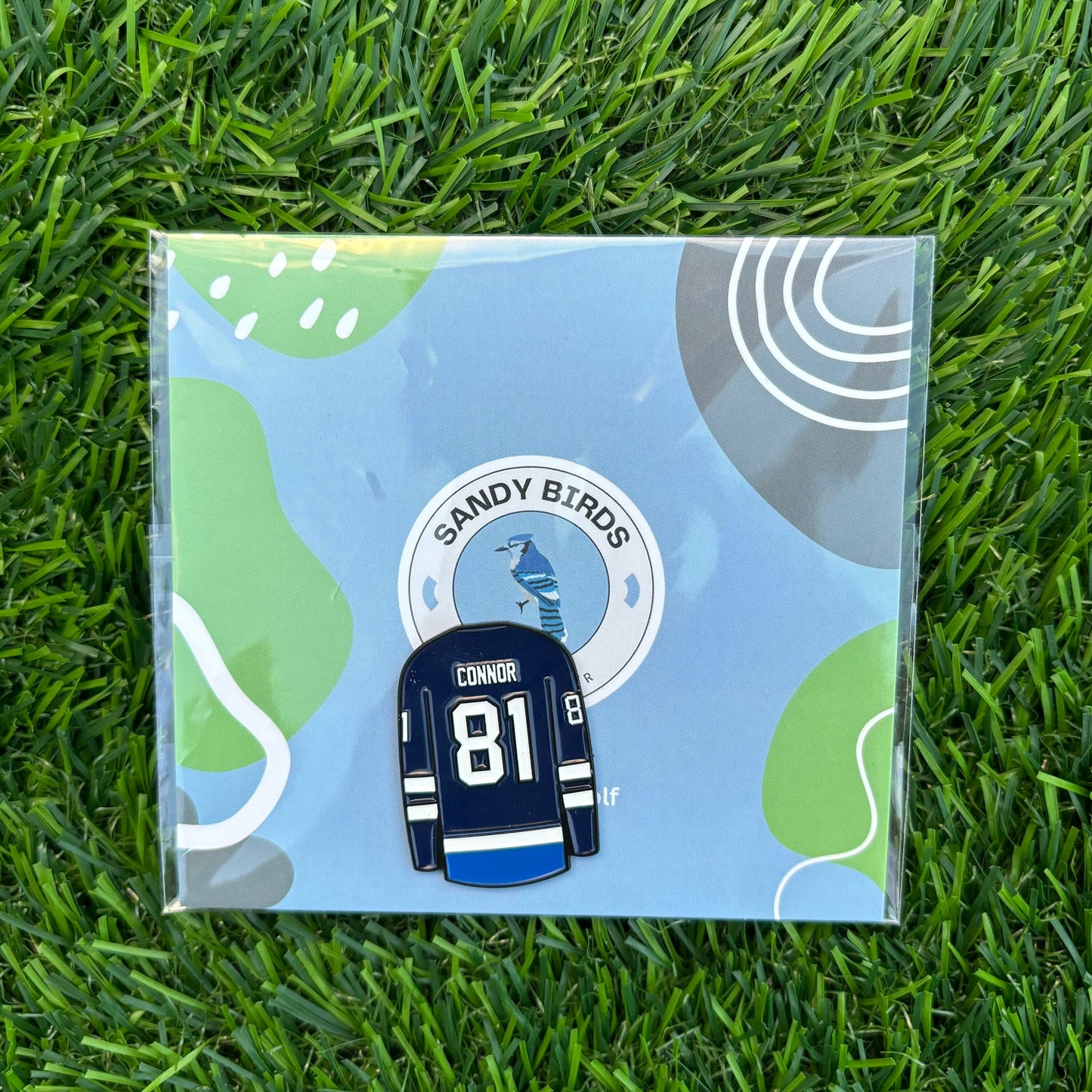 Kyle Connor 81 custom golf ball marker on green grass with Sandy Birds card