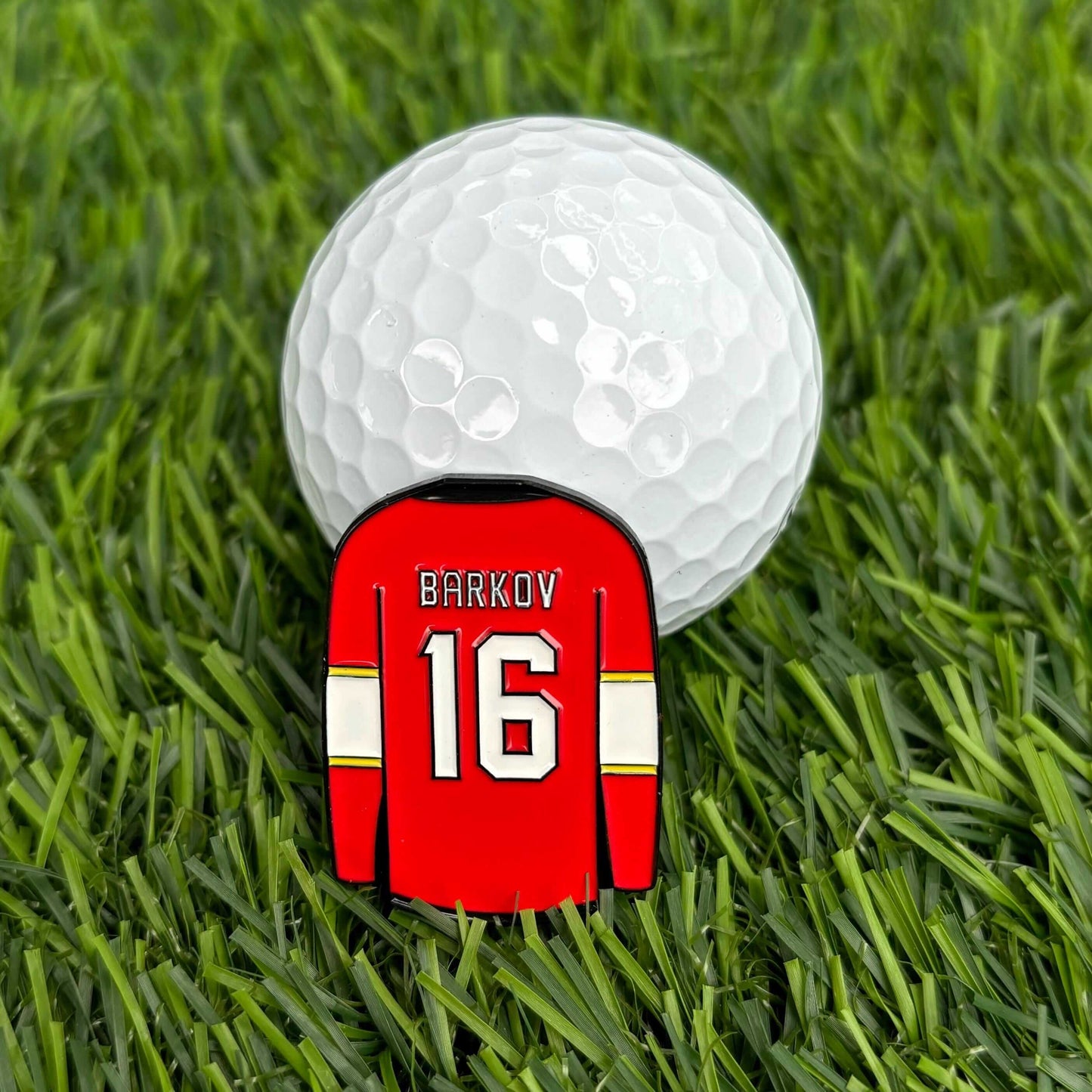 Aleksander Barkov jersey-shaped golf ball marker on green grass with a golf ball, premium and collectible golf accessory for enthusiasts